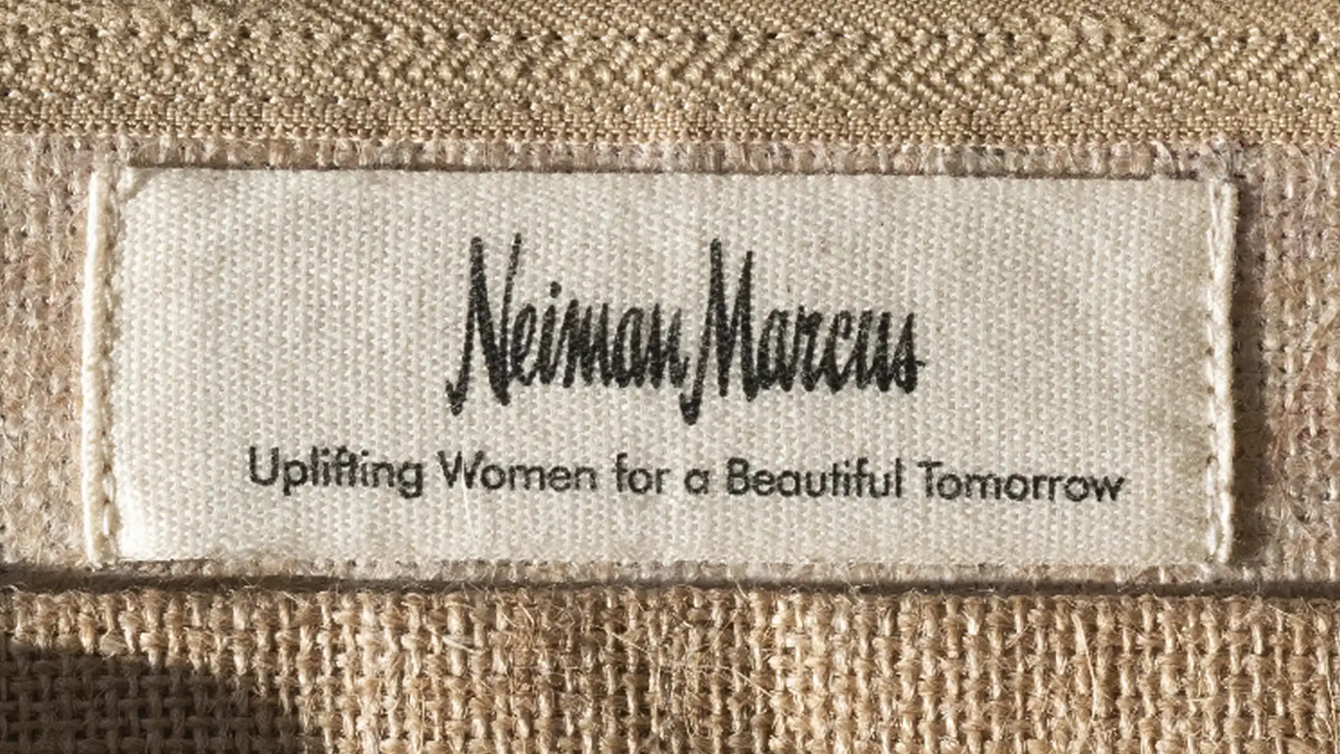 Woven beige bag with a Neiman Marcus label reading Uplifting Women for a Beautiful Tomorrow, from Giving Luxury A Lift