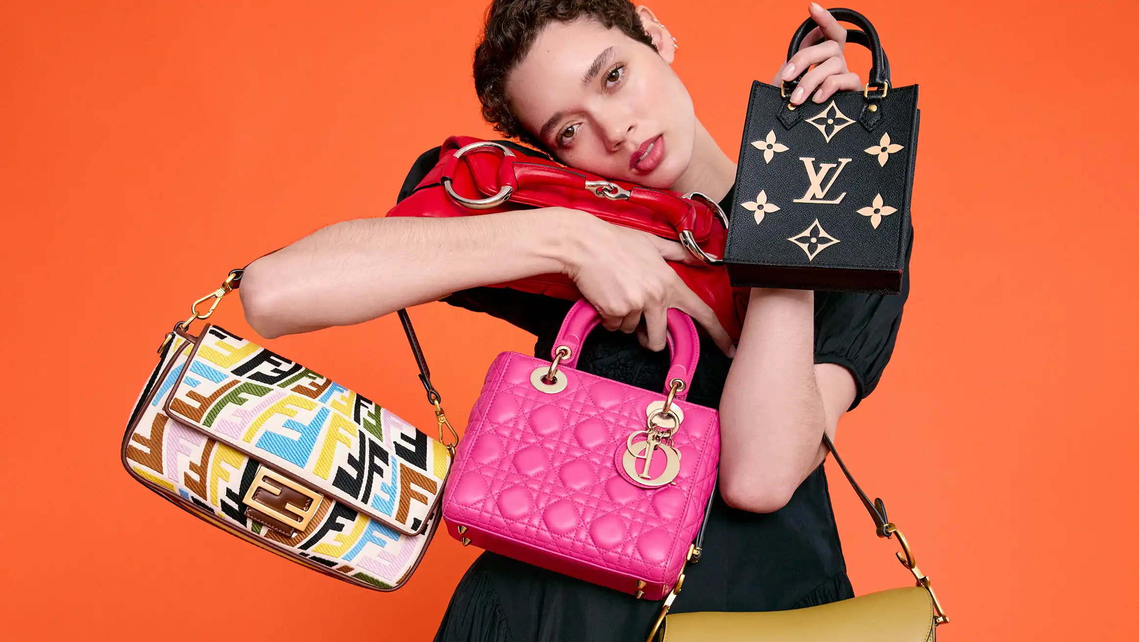 A model holds Fendi, Dior, Louis Vuitton, and red handbags against an orange backdrop for Vestiaire Collective