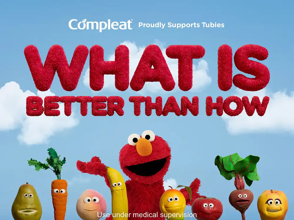 Elmo stands among smiling produce under Compleat Proudly Supports Tubies and What Is Better Than How