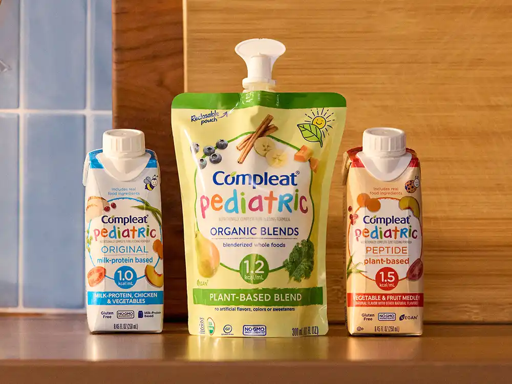 Three Compleat Pediatric cartons and an Organic Blends pouch stand on a kitchen counter, from What Is Better Than How