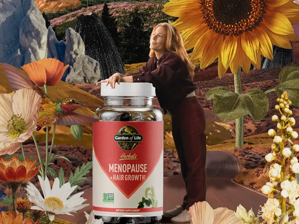 A woman leans on a giant Garden of Life Menopause + Hair Growth bottle among sunflowers, from Formulas for Feeling Alive