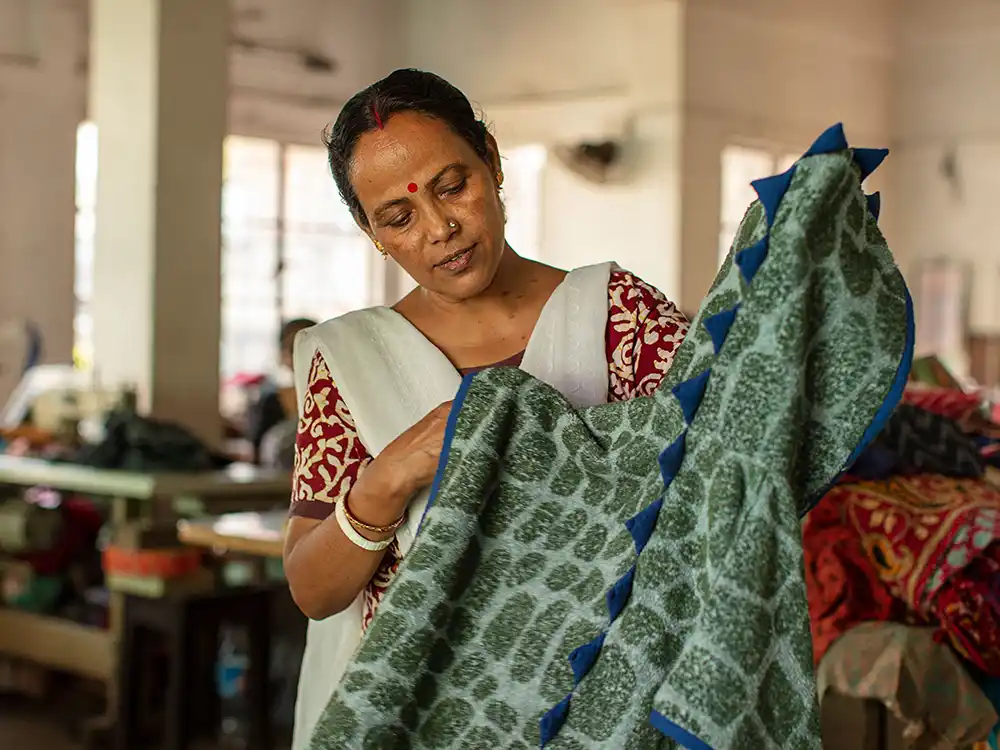 Woman in a workshop inspects a green dinosaur-print hooded towel, from Jurassic World's Preserving Legacies of the Past collection