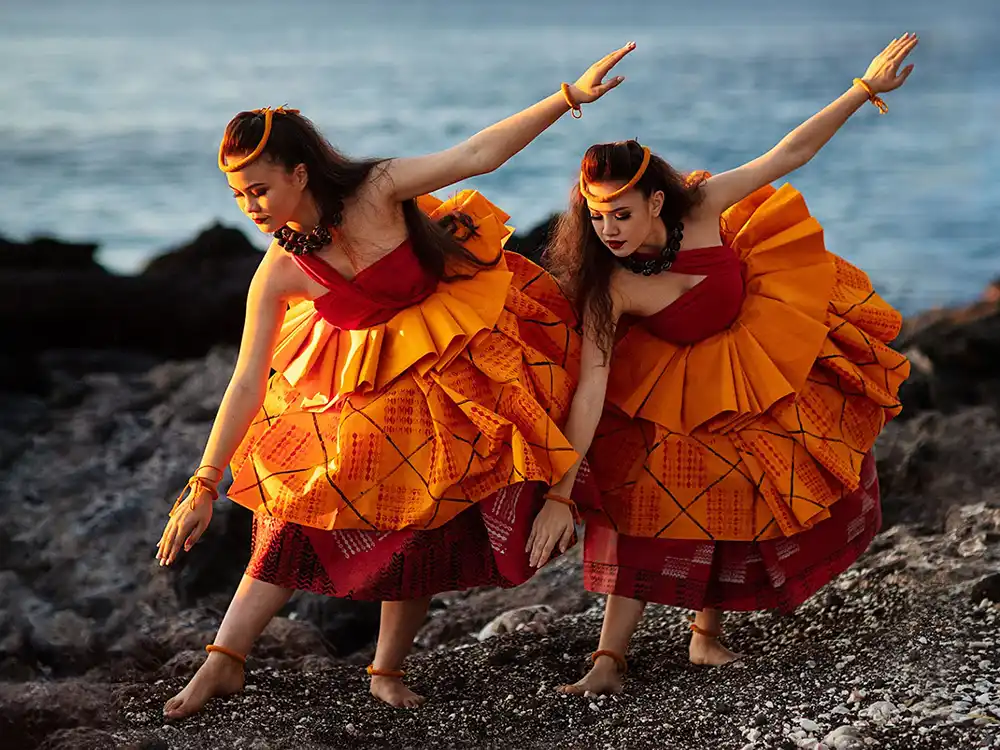 Two dancers in orange ruffled dresses pose on a rocky shore at dusk, from Nespresso's Innovation You Can Taste