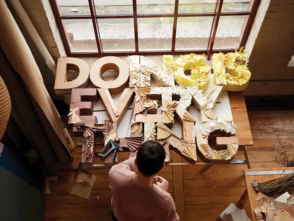 Person assembles cardboard DOING EVERYTHING letters on a studio table, from Nespresso's Innovation You Can Taste
