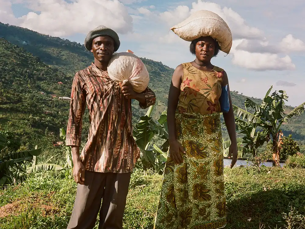 A man and woman carry coffee sacks on a green hillside, from Nespresso's Innovation You Can Taste