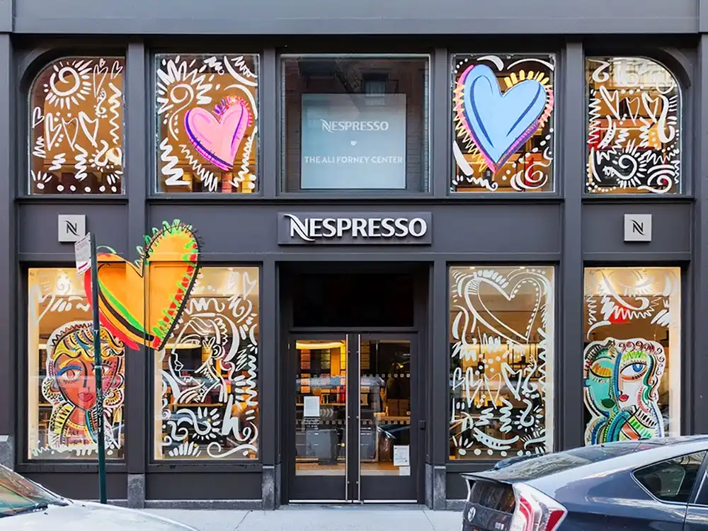 Nespresso storefront with neon hearts, painted faces, and Ali Forney Center signage, from Innovation You Can Taste