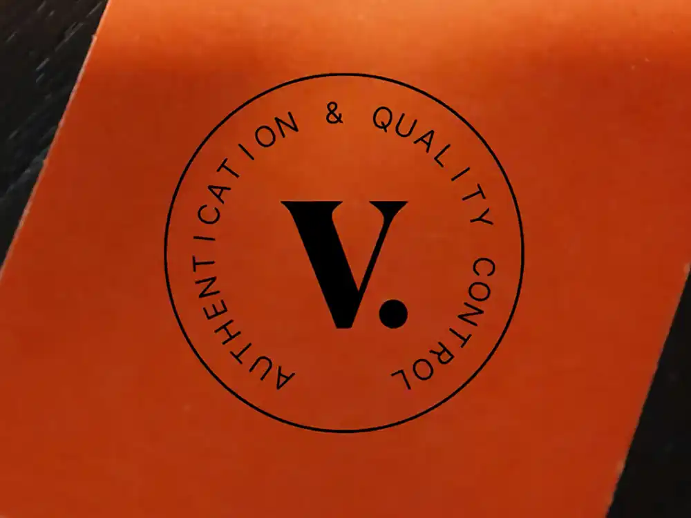 Orange Authentication & Quality Control seal with a V. mark, from Vestiaire Collective's Parlez-vous?
