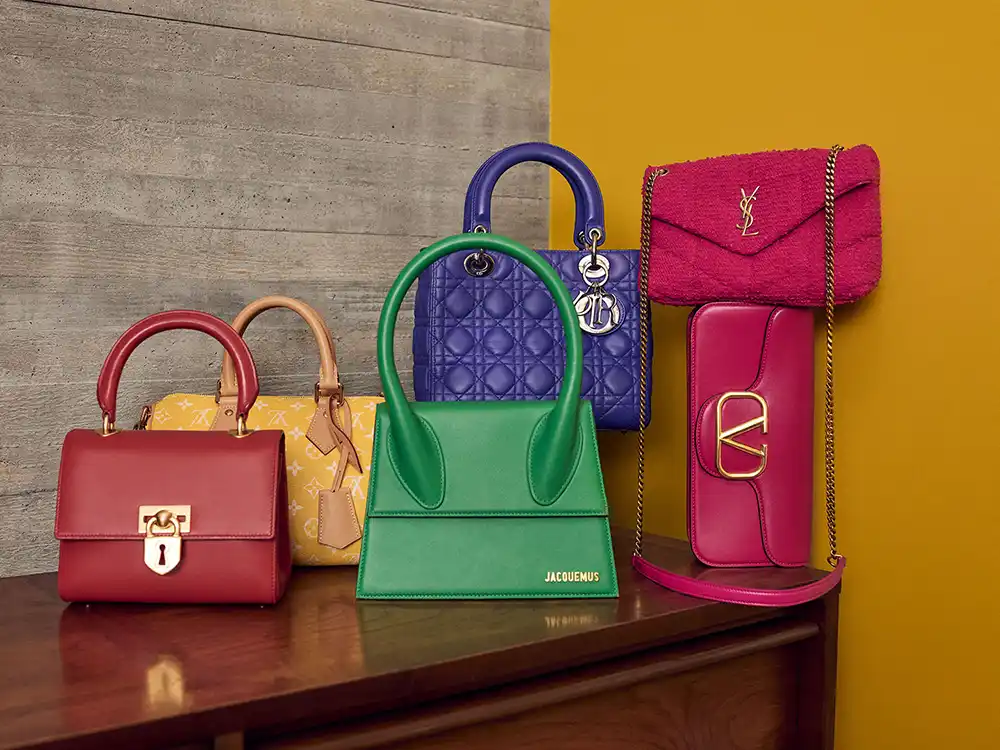Luxury handbags including Jacquemus, Dior, and YSL arranged on a wood cabinet, from Vestiaire Collective's Parlez-vous?