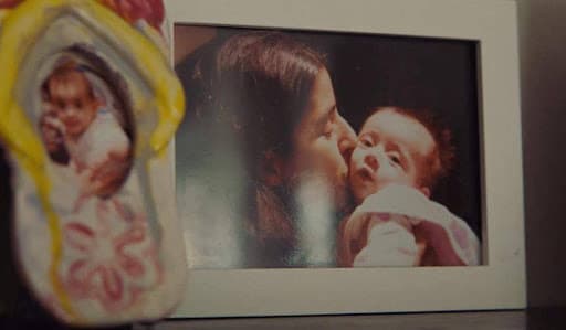 A framed photograph of Avni kissing baby Sonu, with a clay keepsake in the foreground