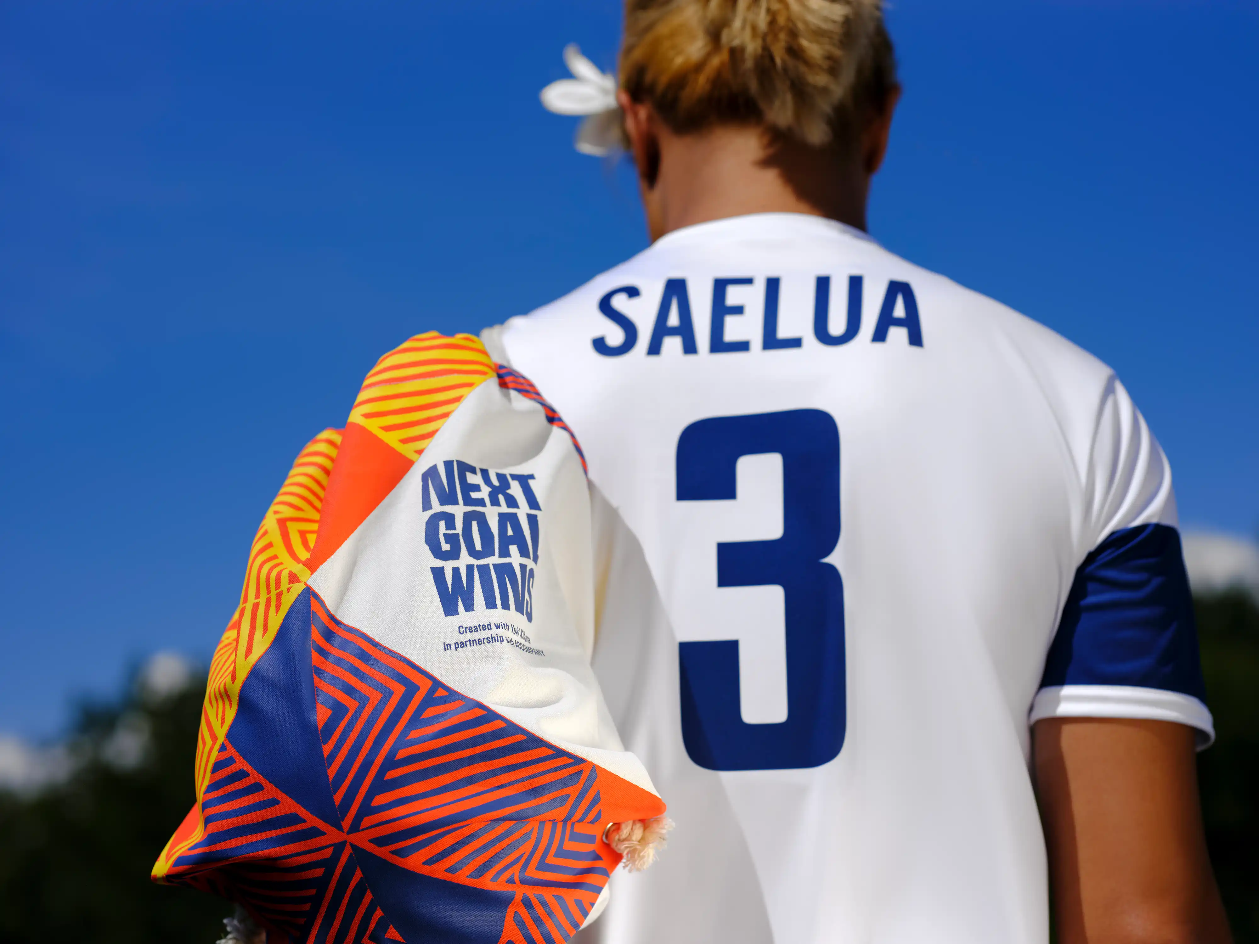Person in Saelua jersey carrying a Next Goal Wins patterned backpack