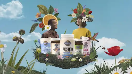 Garden of Life bottles rest on a floating moss island as two people with floral crowns look across a blue sky